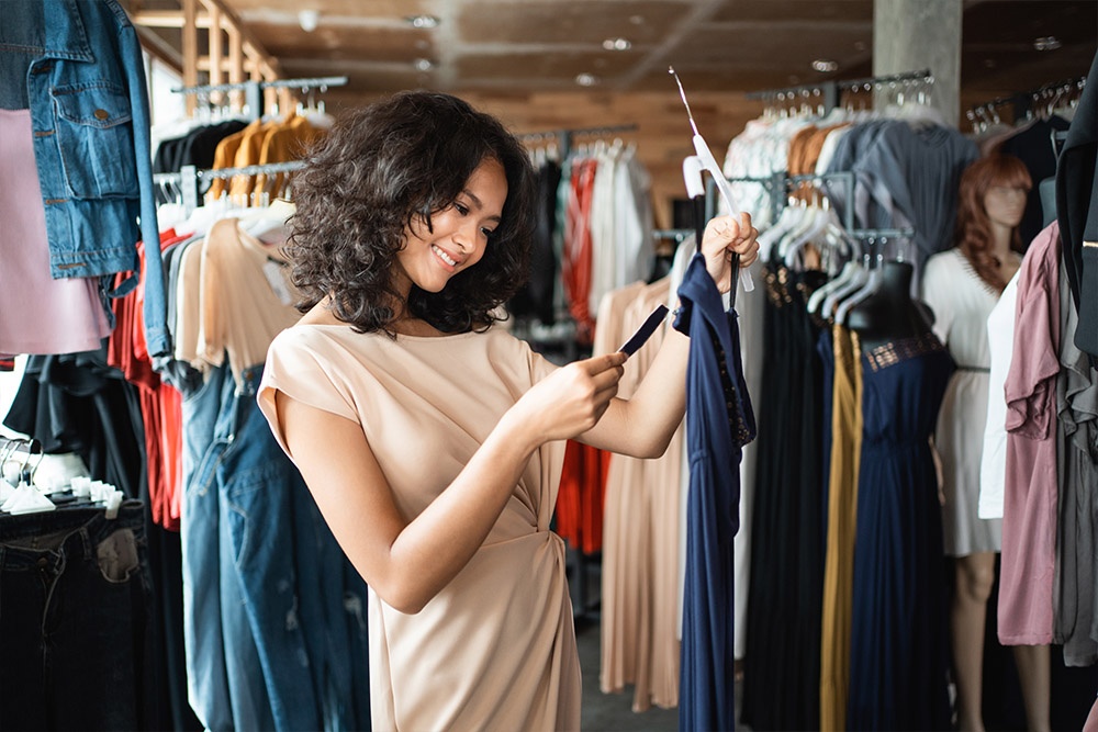 smiling woman looking at price tag on dress